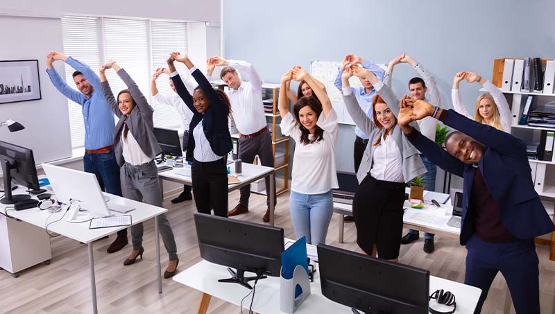 An office team stretching in office together